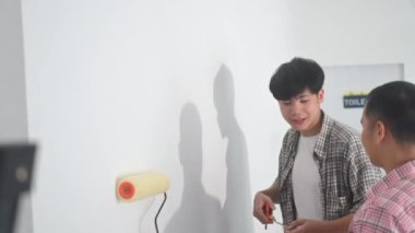 Duvarı ölçen iki genç adam bir ev geliştirme projesine hazırlanıyor..