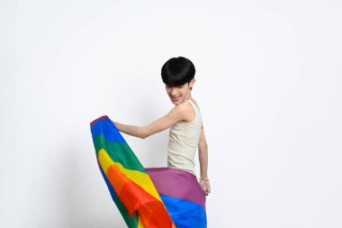 Beyaz arka planda gökkuşağı bayrağı taşıyan neşeli genç bir adam. LGBTQ gurur ve eşitlik kavramı.
