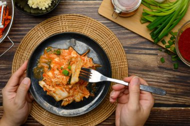 Elleri çatal ve taze hazırlanmış kimchi tabağı taşralı ahşap masada tadını çıkarmaya hazır..