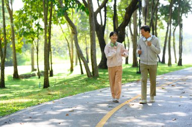 Mutlu yaşlı bir adam ve kızı egzersiz rutininden zevk alıyorlar, birlikte parkta koşuyorlar..
