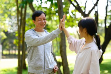 Orta yaşlı bir adam ve kızı dışarıda çalıştıktan sonra beşlik çakıyor. Sağlıklı ve açık hava aktivitesi kavramı.
