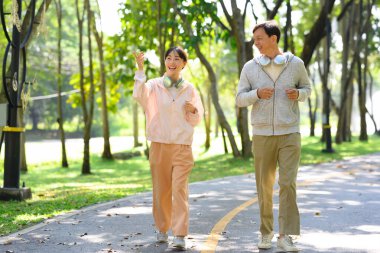 Mutlu yaşlı bir adam ve kızı egzersiz rutininden zevk alıyorlar, birlikte parkta koşuyorlar..