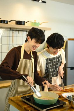 Şefkatli eşcinsel çift mutfak tezgahında yemek hazırlıyor. Taze malzemelerle çevrili..