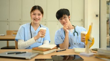 Önlüklü gülümseyen tıp öğrencileri kampüsteki derslerine ara veriyor..