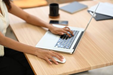 Ahşap ofis masasında dizüstü bilgisayarda çalışan bir iş kadınının resmi..