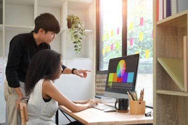 Modern ofiste beyin fırtınası yapan iki meslektaşım bilgisayar ekranında gösterilen tasarım projesini tartışıyorlar..