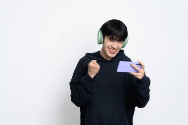 Akıllı telefondan oyun zaferini kutlayan kulaklık takan mutlu bir adam..