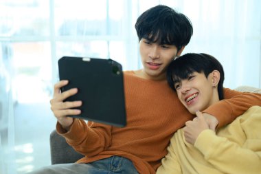 Sevgi dolu genç eşcinsel çift oturma odasında dinleniyor. LGBT, aşk ve yaşam tarzı ilişki kavramı.