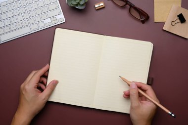 Ellerin açık bir deftere yazışının havadan görünüşü. Yaratıcılık, planlama ve ilham konsepti.