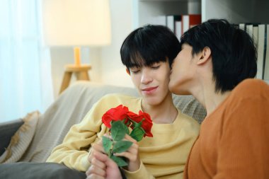 Romantik eşcinsel çift sıcak bir oturma odasında sevgi ve neşe ifade ediyor..