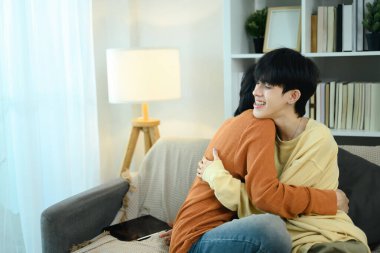 Sevgi dolu eşcinsel çift oturma odalarında birbirlerine sarılıyorlar. Aşk, rahatlık ve LGBTQ ilişkileri kavramı.