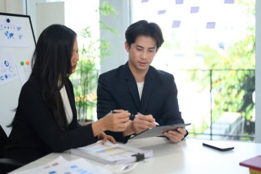 Profesyonel iş ekibi dijital tabletlerle ilgili verileri analiz ediyor ve modern ofiste stratejileri tartışıyor..