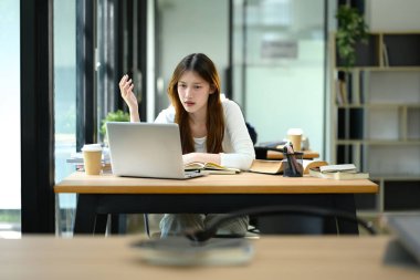 Yoğunlaştırılmış üniversite öğrencisi çevrimiçi öğrenimle uğraşıyor, bilgisayarında çalışma alanı üzerinde çalışıyor..