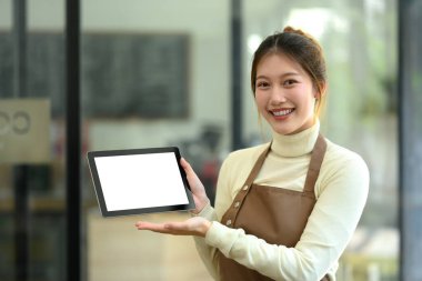 Kendine güvenen bir kahve dükkanı sahibi önlük takıyor ve boş ekranlı dijital tableti gösteriyor..