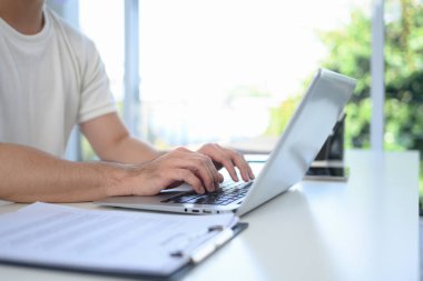 Modern bir ofiste masa başında çalışan dizüstü bilgisayarın klavyesinde yazan elleri kapatın..