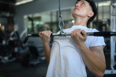 Kararlı sporcu, spor salonunda son sürat aşağı çekmek için kablo kullanıyor..