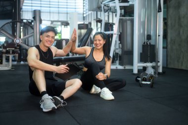 Gülümseyen antrenör ve müvekkil, fitness kilometre taşlarına ulaştıktan sonra beşlik çakıyor.