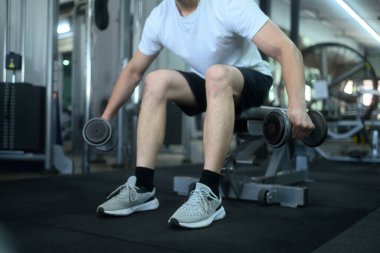 Spor salonundaki halter egzersizine odaklanan güçlü bir genç adam..