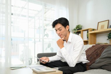 Yetişkin adam, hesap makinesiyle bütçe planlama masraflarını hesaplıyor. Ev finansmanı ve bütçe kavramı.