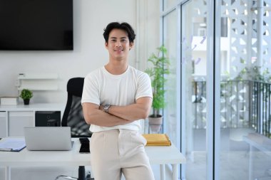 Parlak, modern bir ofiste kolları çapraz duran kendinden emin genç girişimci..