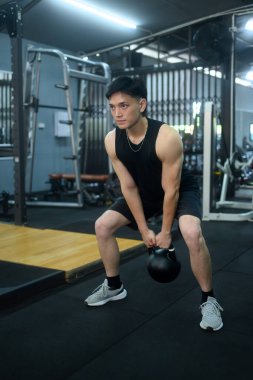 Spor salonunda çaydanlık çanlarıyla egzersiz yapan yakışıklı bir sporcu. Formda, spor ve sağlıklı yaşam tarzı konsepti.