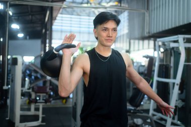 Modern bir spor salonunda kettlebell ile vücudunun üst kısmı üzerinde çalışan yakışıklı bir adam..