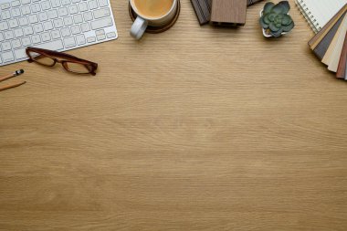 Klavye, bardak, kahve, kalem, sulu bitki ve ahşap kumaşlı ahşap masa..