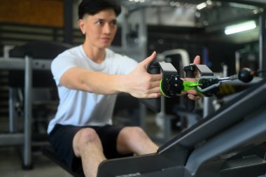 Spor salonunda spor yapan ve ağırlık çeken genç bir sporcu..