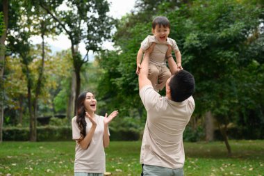 Küçük oğlunu havaya kaldıran mutlu baba birlikte dışarıda vakit geçirmeyi seviyor..
