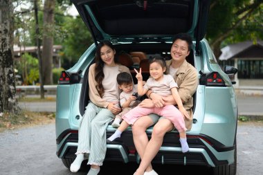 Neşeli bir aile arabalarının açık bagajında oturup yolculuklarının keyfini çıkarıyorlar..