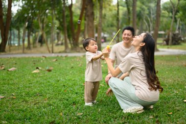 Küçük çocuk yemyeşil bir parkta ailesiyle oynuyordu..