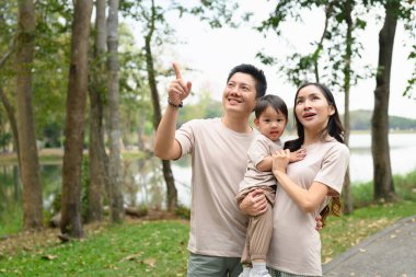 Halk parkında yürüyen mutlu bir aile. Açık hava eğlencesi ve aile bağları kavramı.