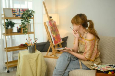 Düşünceli bir sanatçı, rahat bir ev stüdyosunda çalışmalarını düşünüyor..