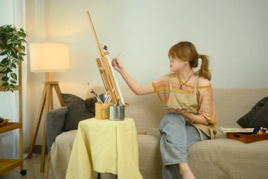 Önlük giyen odaklanmış sanatçı bir sanat stüdyosunda sanat eserleri yaratıyor..