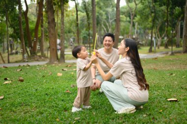 Ebeveynler ve küçük çocuklar doğada kabarcıklarla oynuyorlar. Aile bağı kavramı.