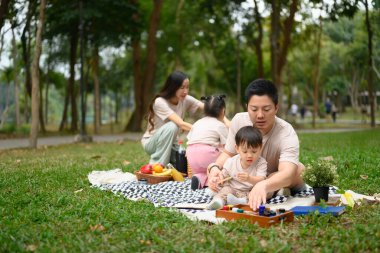Sevgi dolu baba parkta piknik yaparken küçük çocuğuna resim öğretiyor..