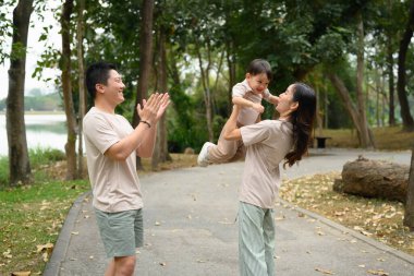 Mutlu ebeveynler ve küçük oğlu manzaralı bir yolda yürüyor. Aile bağı ve açık hava eğlencesi konsepti.