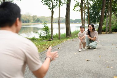Heyecanlı küçük çocuk parkta kollarını açmış babasına koşuyor..