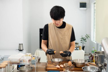 Erkek fırıncı yumurta kırarak karıştırıyor ev yapımı kurabiyeler hazırlıyor..