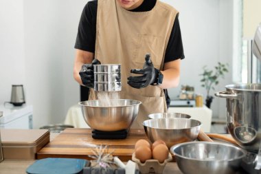 Kurabiye hamuru malzemelerini hazırlarken fırıncı unu elemek.