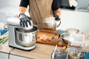 Erkek fırıncı kurabiye hamuru yapmak için karıştırıcı kullanıyor..