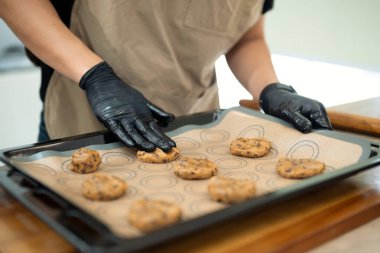 Çikolata parçacıklı kurabiye toplarını pişirme tepsisine koyan adama yaklaş..