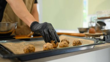 Çikolata parçacıklı kurabiye toplarını pişirme tepsisine koyan adama yaklaş..