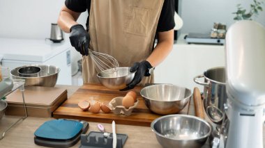 Siyah eldivenli adam kurabiye hamuru için paslanmaz çelik kasede malzeme çırpıyor..