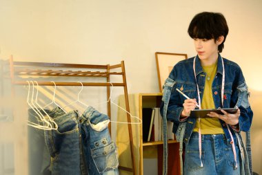 Dijital tablet kullanan yaratıcı tasarımcı şık bir stüdyoda yeni bir koleksiyon üzerinde çalışıyor..