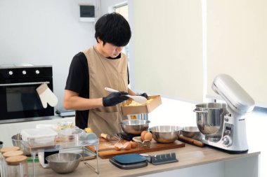 Eldiven giyen genç fırıncı kurabiye hamuru için malzeme hazırlıyor..