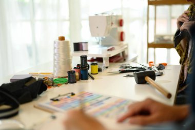 Dikiş araçları, renkli iplik makaraları ve kumaş örnekleriyle dolu yaratıcı çalışma alanı.