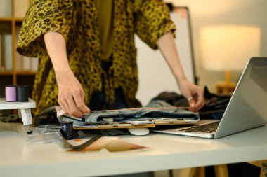 Yaratıcı bir moda stüdyosunda kot ceket ve mezurayla ölçüm yapan genç bir tasarımcı..