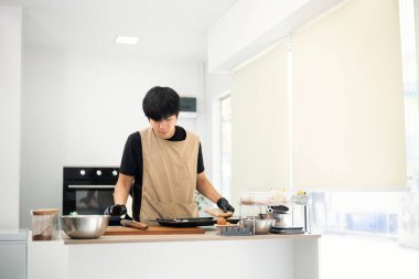 Yakışıklı Asyalı genç adam kurabiye tepsisinde kurabiye hamuru düzenliyor..