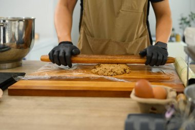 Bir fırıncının, çikolatalı kurabiye hamurunu tahta bir oklavayla dümdüz etmesini..